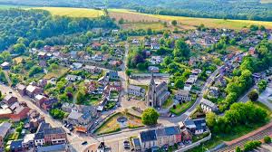 Vue sur la charmante rue de Hamoir avec entreprise locale de vidange, maisons en pierre et architecture typique de la région.