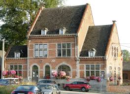Centre-ville de Honnelles avec une camionnette de vidange passant devant des maisons typiques en briques rouges. Vidange Honnelles