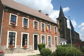 Centre d'Incourt avec camion de vidange, maisons en brique et rues pavées typiques. Requête: Vidange Incourt.