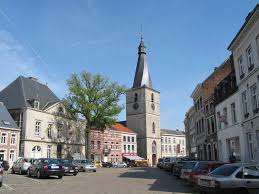 Vidange Jodoigne camions près d'un bâtiment historique en pierre avec rues pavées typiques et arbres verdoyants