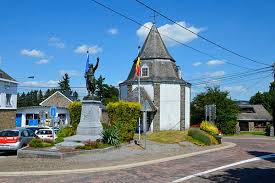 Spécialiste débouchage Lierneux devant une église en pierre emblématique, ruelles pavées et verdure typique de la ville.