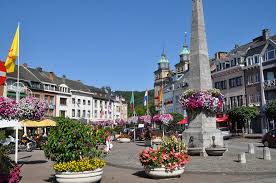 Camion effectuant une vidange à Malmedy devant la cathédrale baroque avec des montagnes en arrière-plan