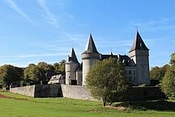 Vidange Onhaye devant une maison en pierre traditionnelle avec des jardins fleuris et rues pavées typiques de la région