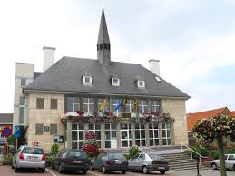 Scène urbaine de Perwez montrant un atelier de vidange auto avec enseigne Vidange Perwez, rue animée et passants.