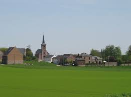 Débouchage Ramillies rue pavée avec maisons de briques anciennes et église en toile de fond, scène typique et charmante