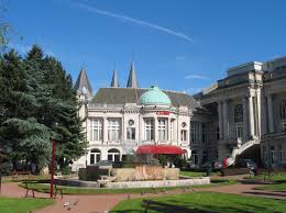Vue sur le centre-ville animé de Spa avec une camionnette de service Débouchage Spa stationnée près d'un bâtiment historique.