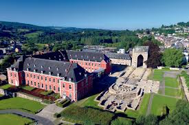 Rue pittoresque de Stavelot avec présence d'un service de débouchage, bâtiments historiques et nature environnante.