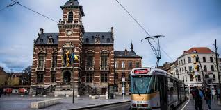Scène urbaine à Anderlecht avec un technicien effectuant un débouchage près d'un bâtiment historique du centre-ville.