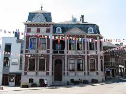 Vue sur une rue pavée de Herve avec un technicien en débouchage travaillant devant une maison typique rénovée