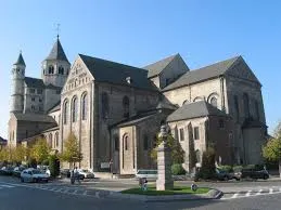 Débouchage Nivelles devant la Collégiale Sainte-Gertrude, rue animée avec commerces et architecture médiévale typique.