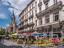 Rue animée de Saint Gilles avec un atelier de vidange auto et façades colorées, typique des quartiers locaux.