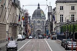 Scène urbaine de Saint Josse Ten Noode avec camion de vidange dans une rue animée entourée d'architectures typiques.