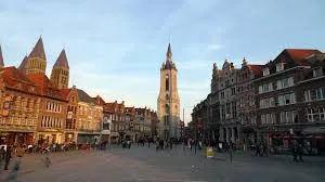 Vue de la cathédrale Notre-Dame à Tournai avec camion de vidange sur rue pavée sous un ciel bleu Vidange Tournai