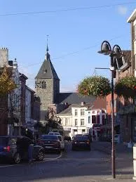 Vue urbaine de Tubize avec un plombier en action pour débouchage, bâtiments en brique typiques en arrière-plan.